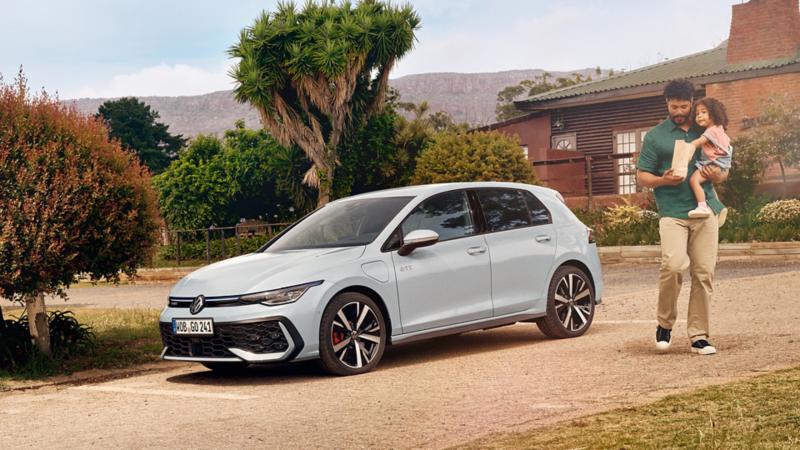 Eine Person steht neben einem weißen VW Golf GTE.