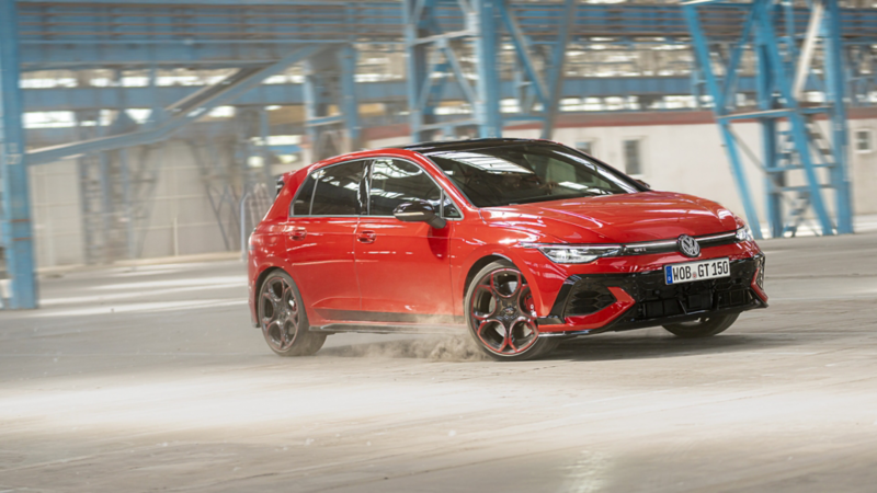 Roter VW Golf GTI EDITION 50 fährt eine Kurve in einer Werkhalle.