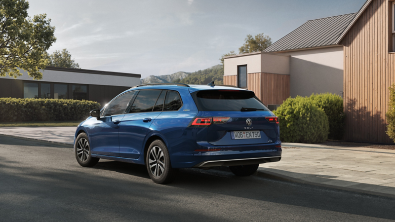 Blauer Volkswagen Golf Variant steht vor modernen Häusern in einer ruhigen Wohnstraße, Rückansicht leicht seitlich