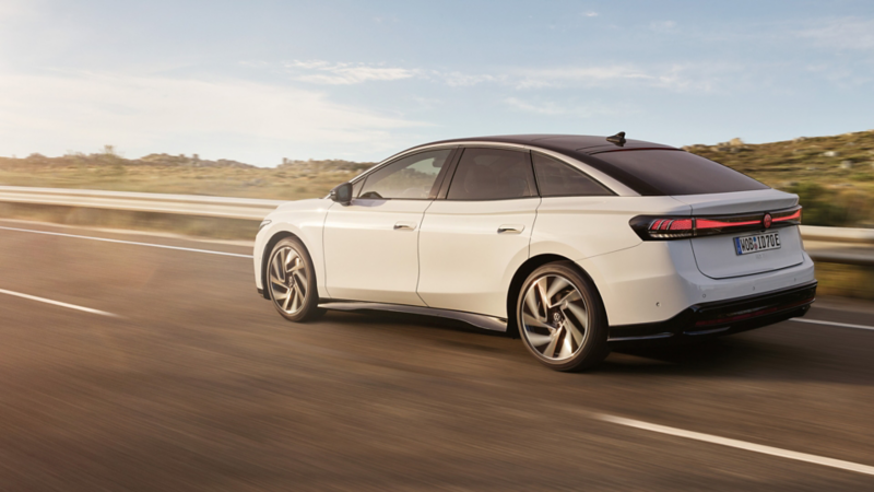 VW ID.7 fährt auf einer Landstraße, Blick auf die aerodynamisch gestaltete Front.