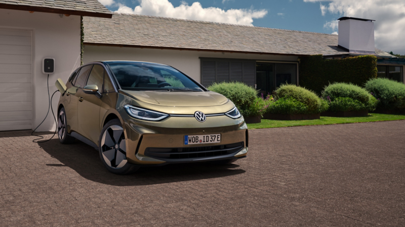 VW ID.3 parkt vor einer Garage und ist an eine Ladestation angeschlossen.