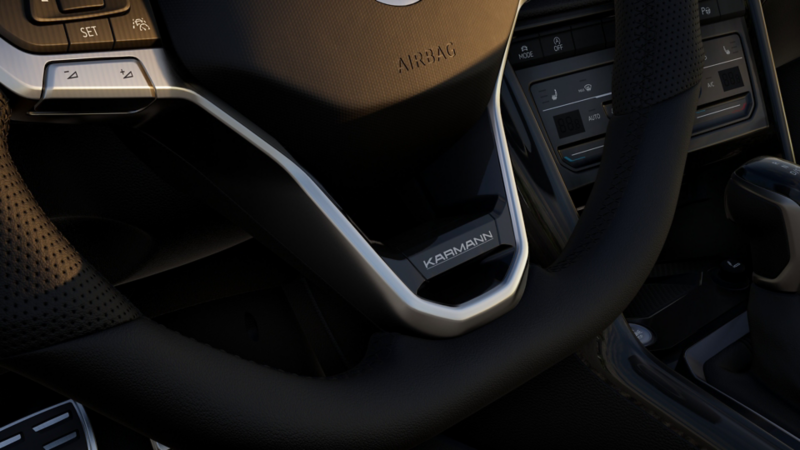 Lenkrad mit Karmann-Logo, integrierten Steuerungstasten und sichtbarem Airbag-Modul im Fahrzeugcockpit