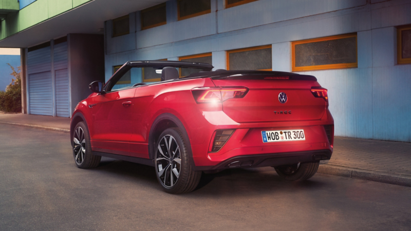 Ansicht des Hecks eines roten T-Roc Cabriolet mit geöffnetem Dach, parkend am Straßenrand. 