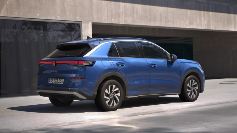 Eine 3/4-Rückansicht eines blauen Volkswagen T-Roc Life, parkend vor einem Gebäude.