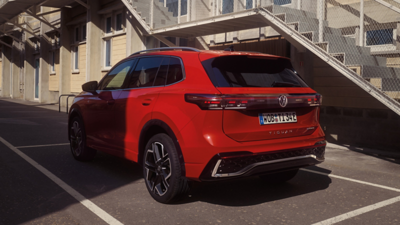 Roter VW Tiguan parkt vor einem mehrstöckigen Gebäude.