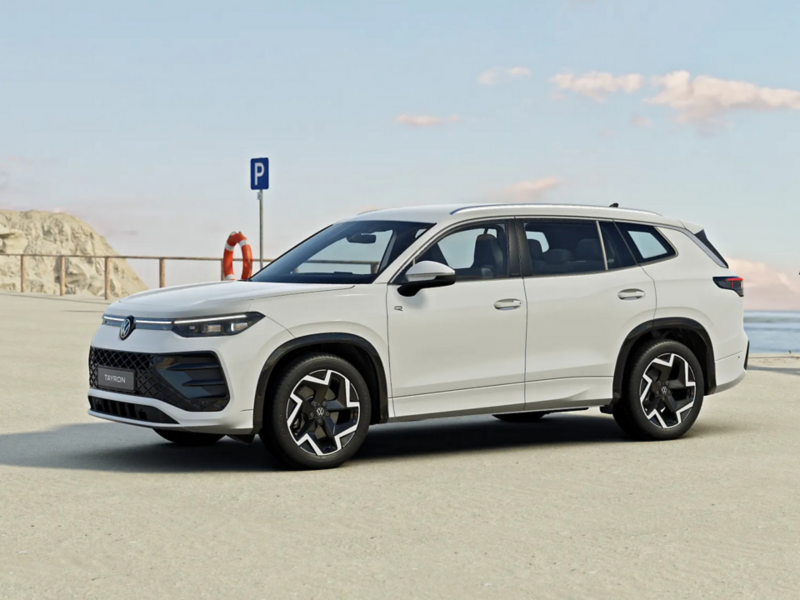 Weißer  VW Tayron R-Line geparkt am Meer mit Rettungsring und Parkplatzschild im Hintergrund