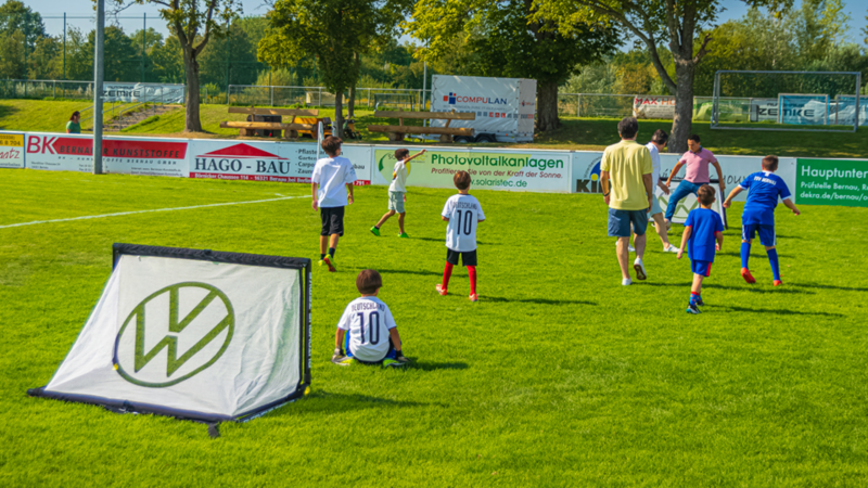 Erwachsene und Kinder spielen gemeinsam Fußball 