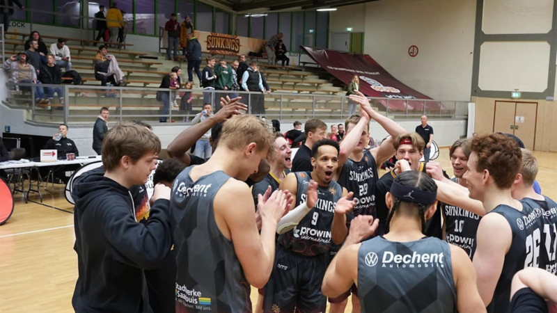 Basketballteam Sunkings in schwarzen Trikots feiert gemeinsam mit Applaus und Jubel in der Halle