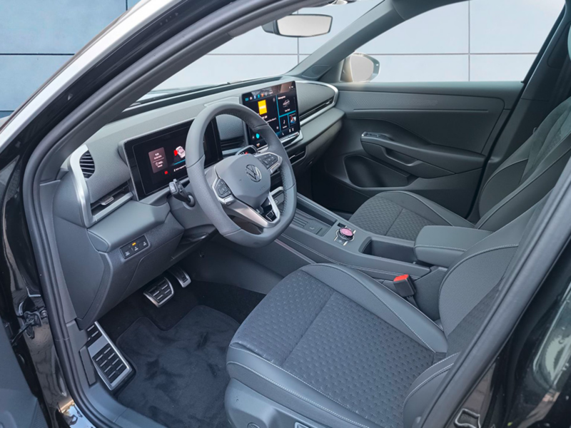 Einblick auf die Fahrerseite eines schwarzen Volkswagen T-Roc Life, dessen Tür geöffnet ist.