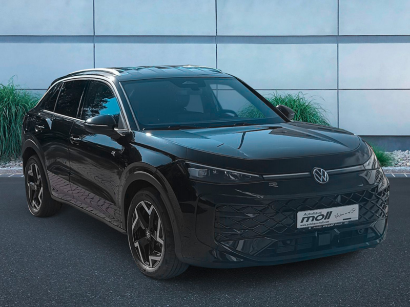 Frontansicht eines schwarzen T-Roc R-Line der vor dem Autohaus Mol in Biberach, einem Gebäude mit viel Glas, steht. 