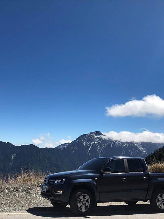 黑色Amarok停在高山路邊，遠方可見山脈及藍天白雲