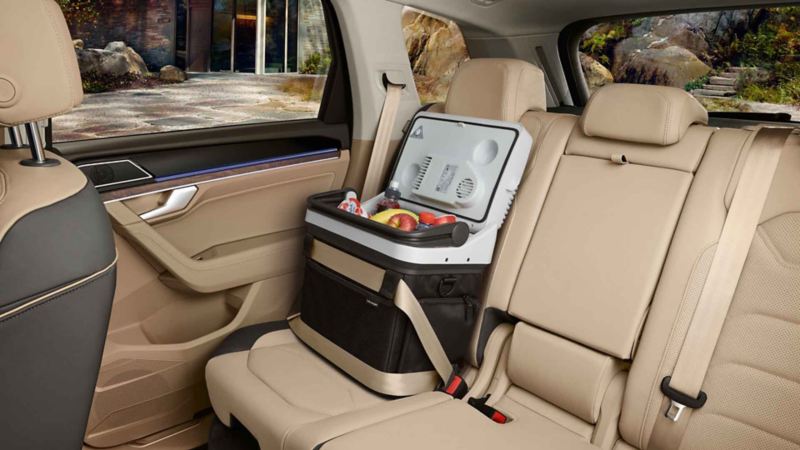 Otwarta lodówka samochodowa wypełniona napojami i owocami, zabezpieczona pasem bezpieczeństwa na tylnym siedzeniu VW Touarega 