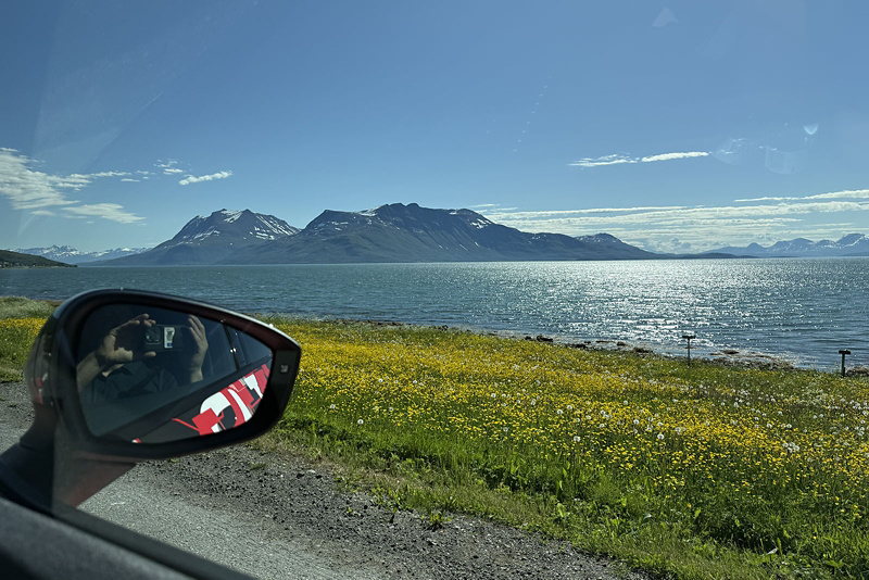 Detaljbild på backspegeln med berg och sjö i bakgrunden