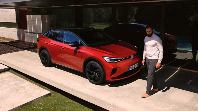 Roter VW ID.5 GTX von schräg vorne in einem modernen Carport, ein Mann geht vor der Motorhaube entlang