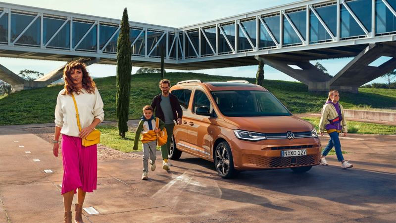 Family walking away from parked Volkswagen Caddy.