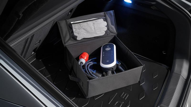 Im Kofferraum eines VW liegt eine Box mit einem Ladekabel.