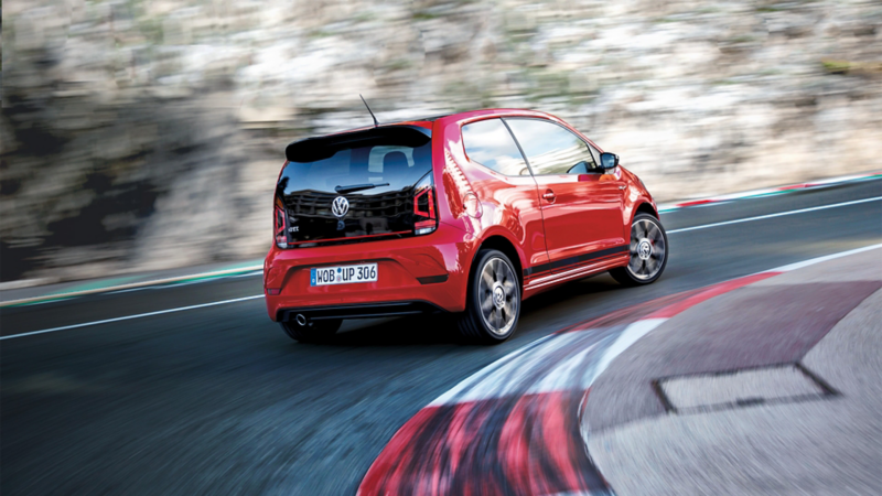 Ein roter VW up! fährt in eine Straßenkurve.