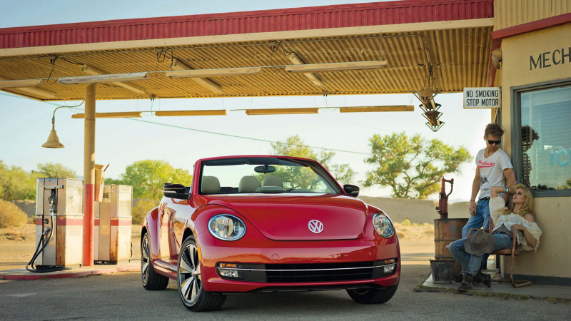 VW beetle convertible with couple next to it