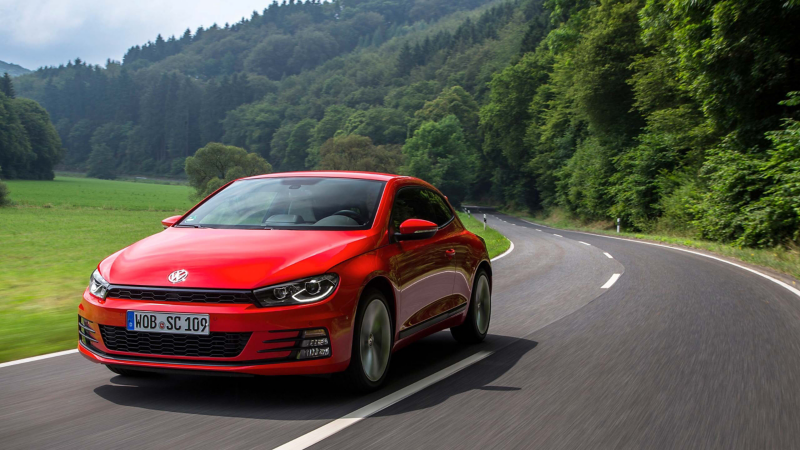 Red VW car driving on road