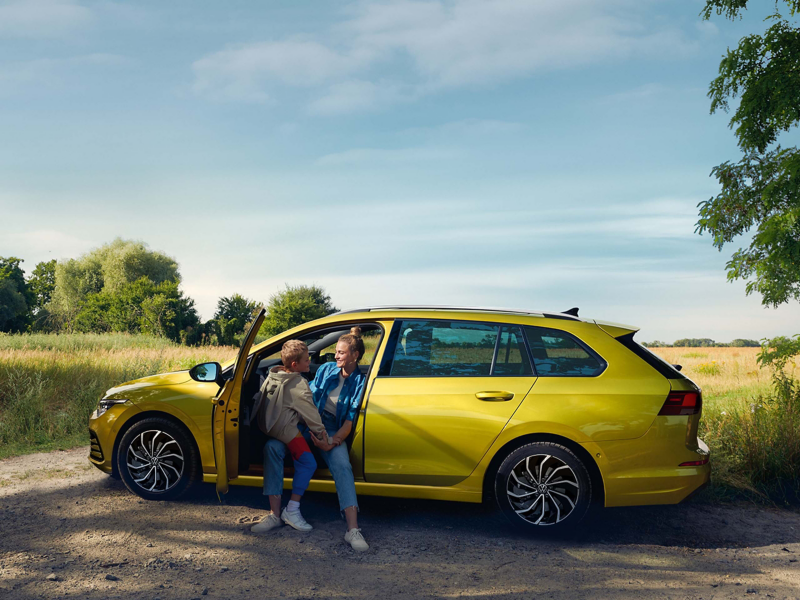 Gold VW car with mother and son sat in front seat with door open