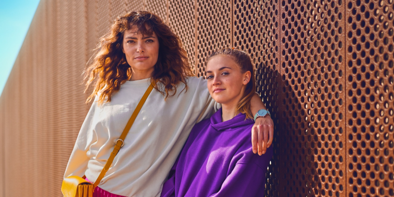 A mother and daughter stand in front of a copper-coloured perforated wall.