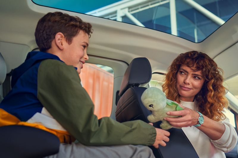 Panoramaglastaket i nya VW Caddy, en mamma ger sin son i baksätet en leksak