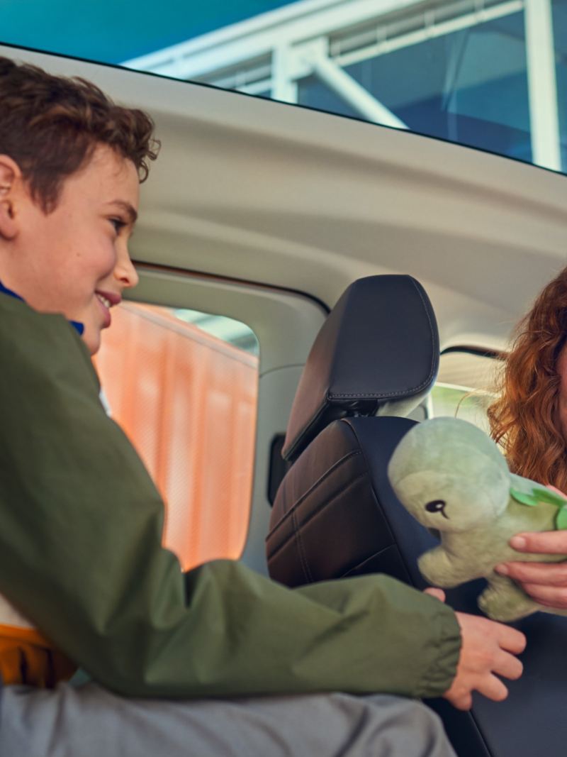 Panoramaglastaket i nya VW Caddy, en mamma ger sin son i baksätet en leksak