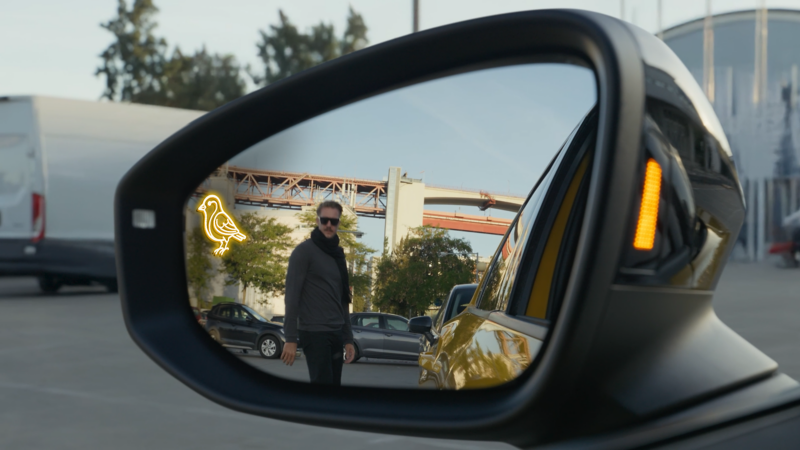 A person reflected in the wingmirror of a T-Roc with the Canary Assist icon in the top left