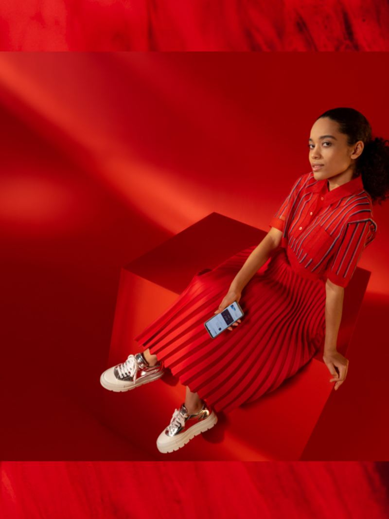 Nastrojowe zdjęcie kobiety ze smartfonem na czerwonym tle