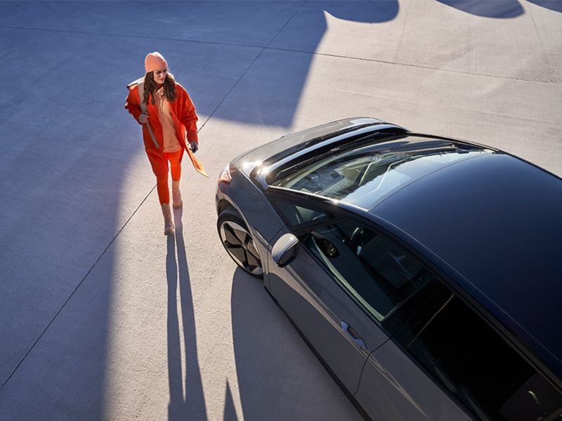Eine Frau geht an der Vorderseite eines VW ID. entlang.