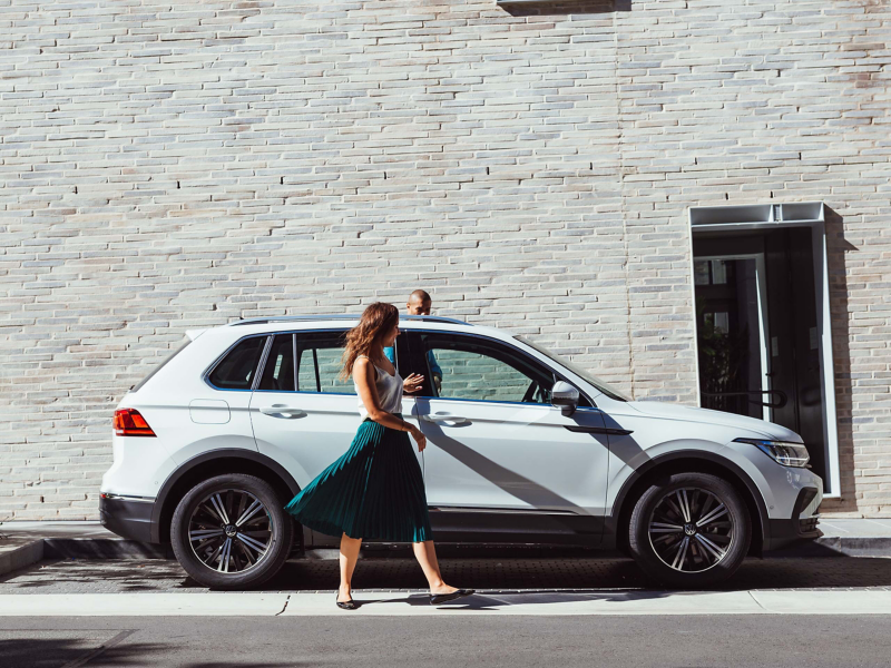 Woman opening car door of white VW