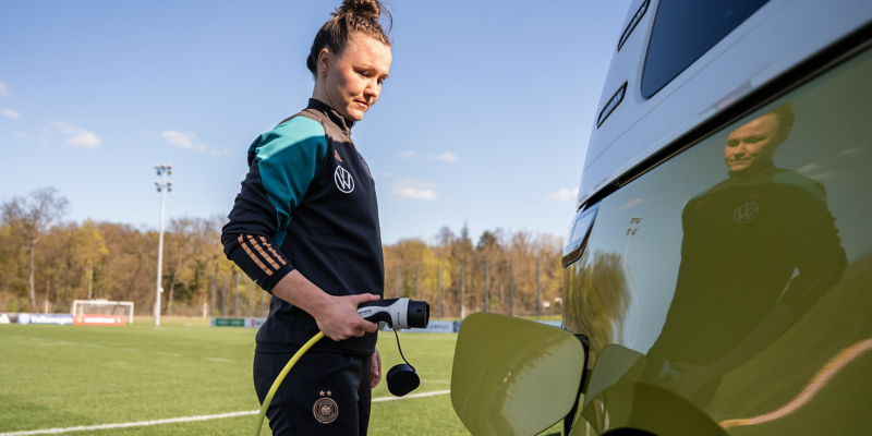 Eine DFB Spielerin beim Ladevorgang des VW ID. Buzz.