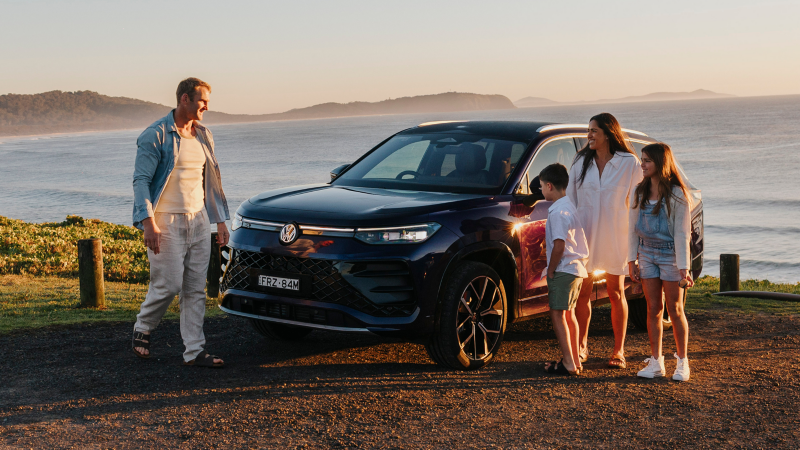 Family stood around Tayron car with ocean in background