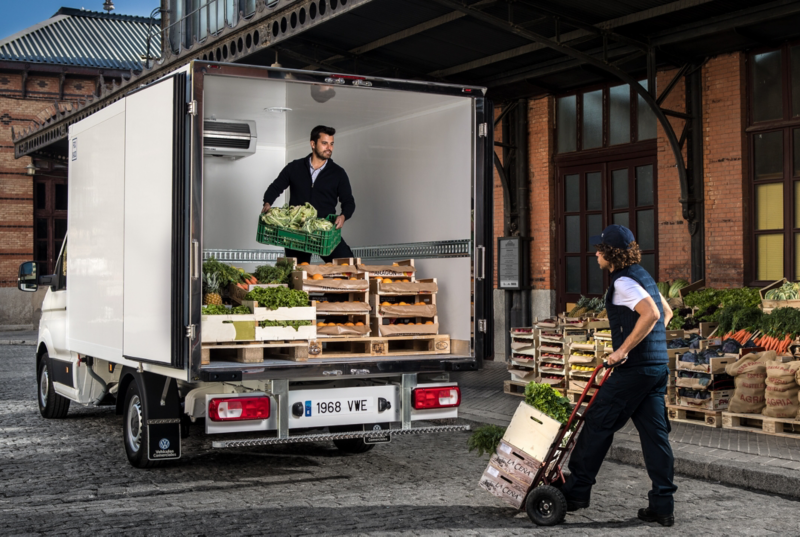 Dos trabajadores cargando unas cajas con alimentos en la parte trasera del VW Crafter Fresh