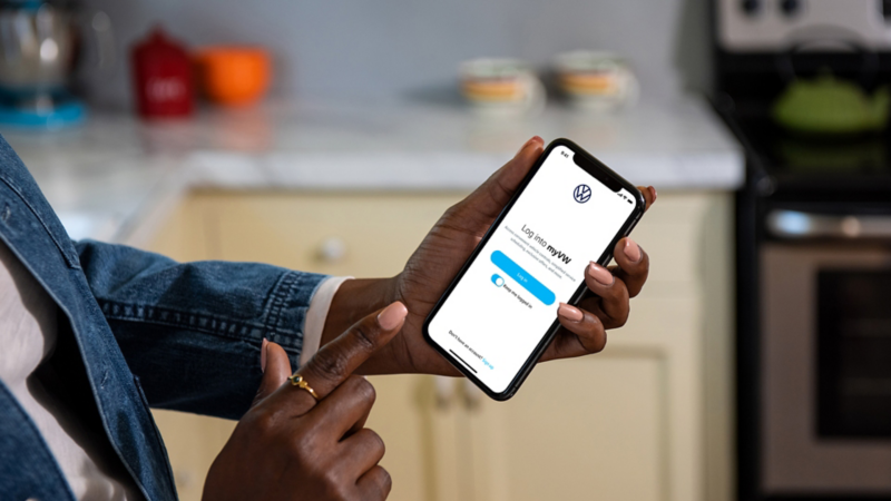 A close-up on a smartphone a woman is holding. On the screen we can see she’s logging into the myVW app.