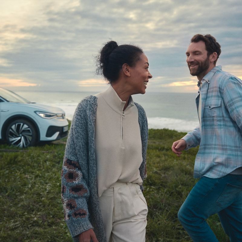 Ein Paar läuft durch die Natur. Im Hintergrund steht ein weißer VW ID.5.