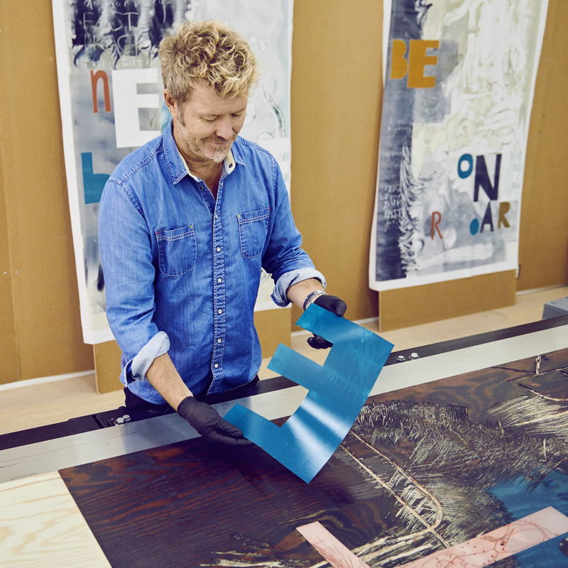 Magne Furuholmen en train de peindre des lettres dans son atelier.