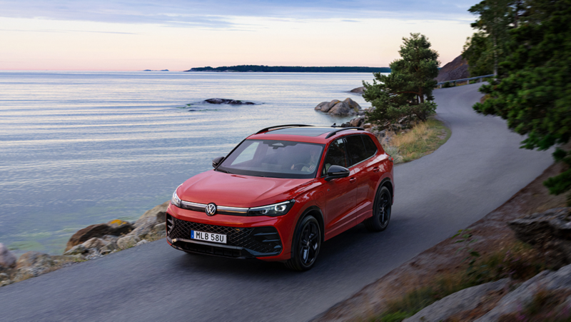 En röd Tiguan eHyrid kör längs väg precis vid havet