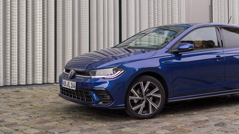 Seitenansicht auf blauen VW Polo. Frau schaut aus dem Fenster.