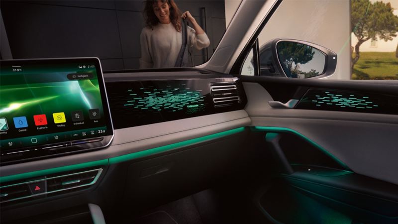 Innenansicht VW Tiguan nachts, Farbdisplay zeigt Einstellungen des optionalen Ambientelichts, Innenraum grün beleuchtet.