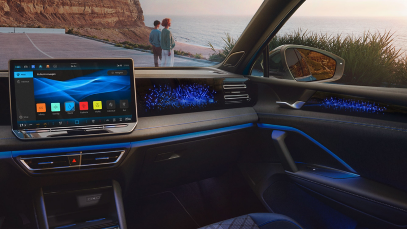 VW Tiguan mit blauer Ambientebeleuchtung. Durch die Frontscheibe ein auf das Meer schauendes Paar sichtbar.