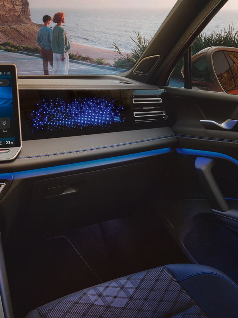 Vue intérieure du VW Tiguan, l'écran affiche les réglages d'éclairage d'ambiance en option, l'habitacle est illuminé en bleu.