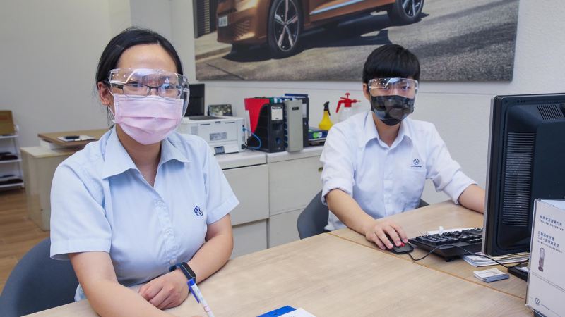 兩位坐在電腦前的福斯工作人員，都有戴好口罩以及防疫面罩
