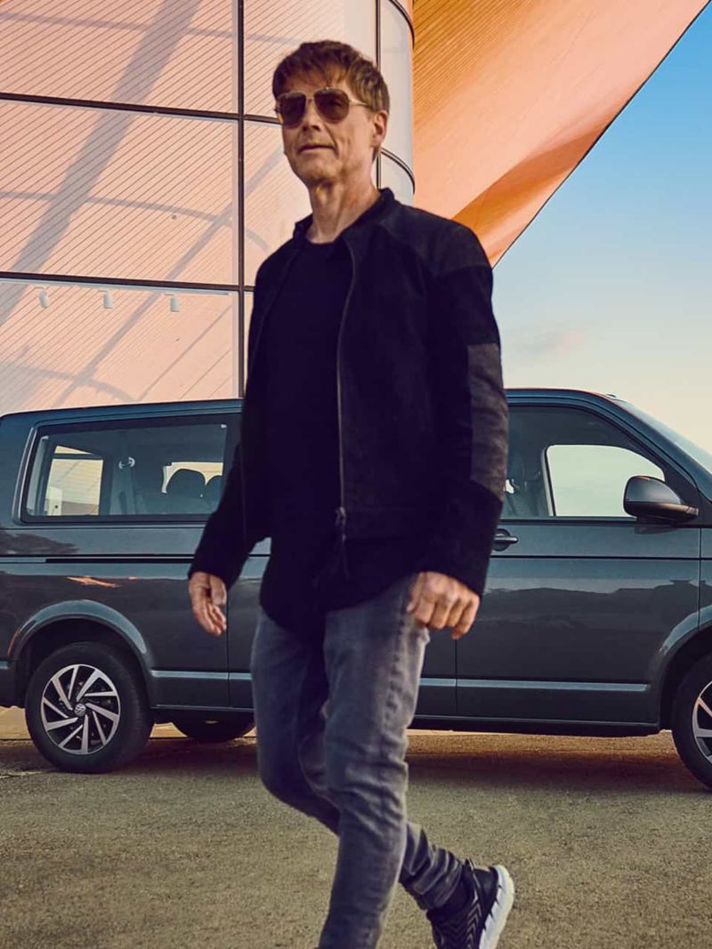 Morten Harket en train de marcher devant une Caravelle Volkswagen Véhicules Utilitaires.