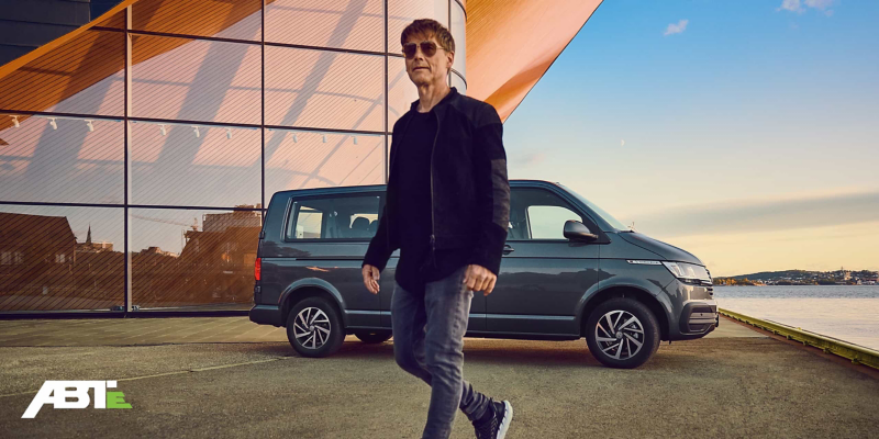 Morten Harket en train de marcher devant une Caravelle Volkswagen Véhicules Utilitaires.