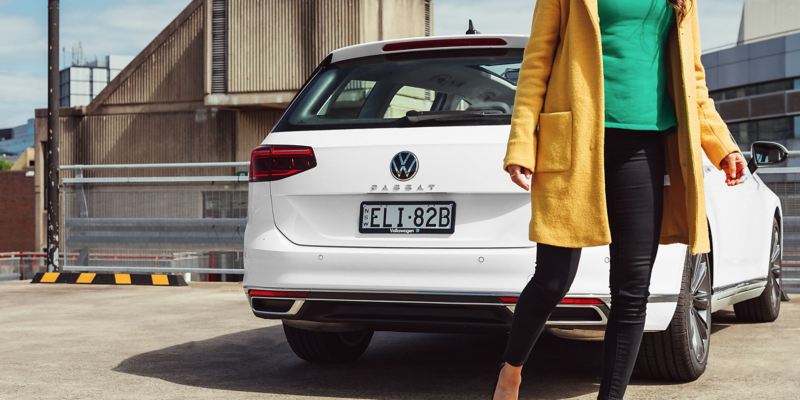 Woman walking past Volkswagen Passat Wagon in background.