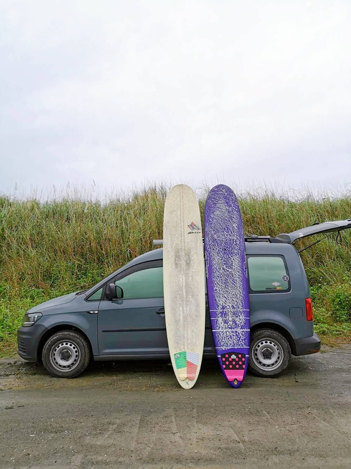 兩塊長板靠著鏡色灰的Caddy Van車側立在地板上，車尾門掀起