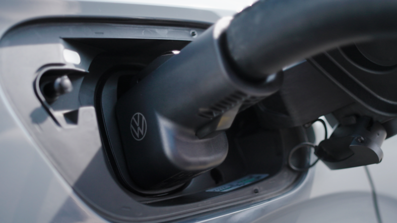 Volkswagen ID.4 charging with NACS DC fast-charging adapter at a Tesla® Supercharger station.