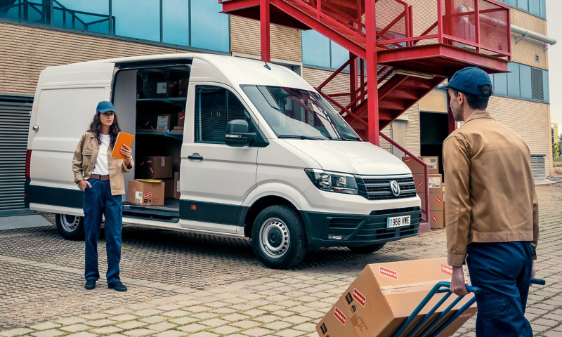 Una pareja de trabajadores cargando paquetes en el interior del VW Crafter Carrier