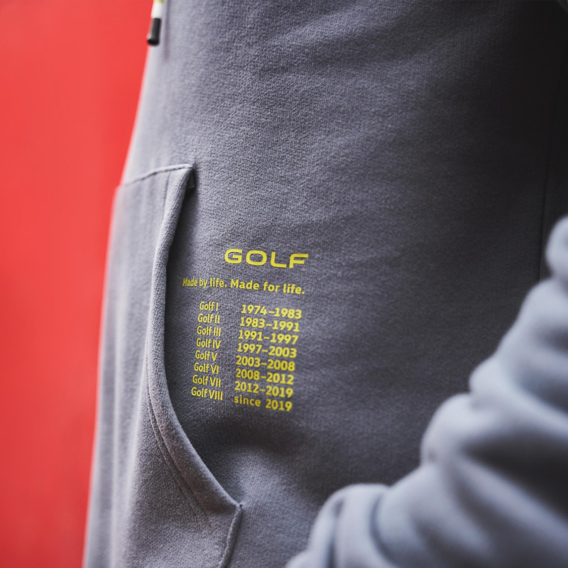 Graues Sweatshirt aus der Golf Kollektion mit gelbem Schriftzug der einzelnen Baureihen und deren Produktionszeiträume